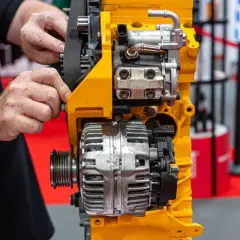 Ręce mechanika regulują pasek na alternatorze, kluczowym elemencie silnika.