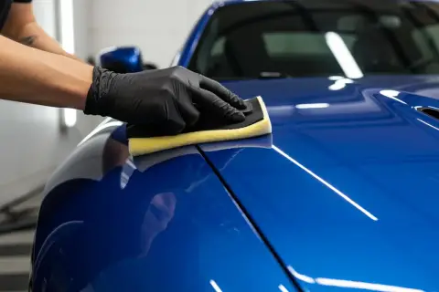Nakładanie ceramiki na auto to inwestycja w jego wygląd i ochronę. Rękawiczka z gąbką rozprowadza produkt po lśniącym lakierze.