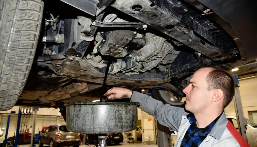Mechanik spuszcza olej z silnika samochodu. Zastanawiasz się, ile trwa wymiana oleju? Zwykle to szybka czynność.