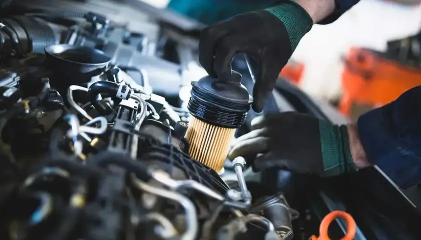 Mechanik wymienia filtr paliwa. Objawy jego zużycia mogą być różne, od spadku mocy po problemy z uruchomieniem silnika.