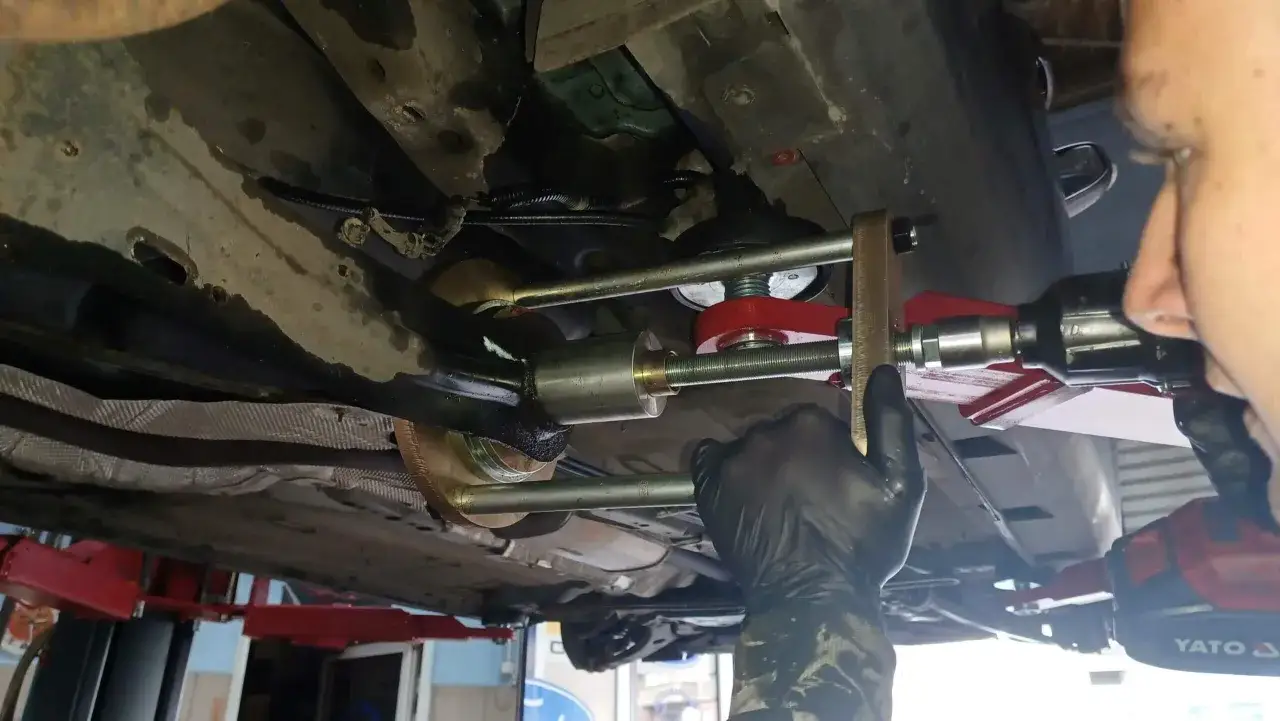 Mechanik dokonuje wymiany tulei wahacza przy użyciu specjalistycznego narzędzia.