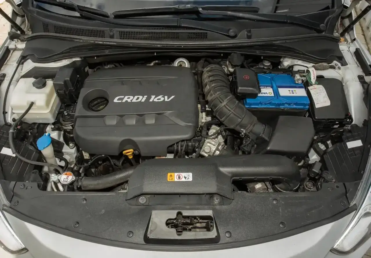 Silnik Kia Sportage 1.7 CRDi. Widoczny blok silnika, akumulator i elementy układu dolotowego.